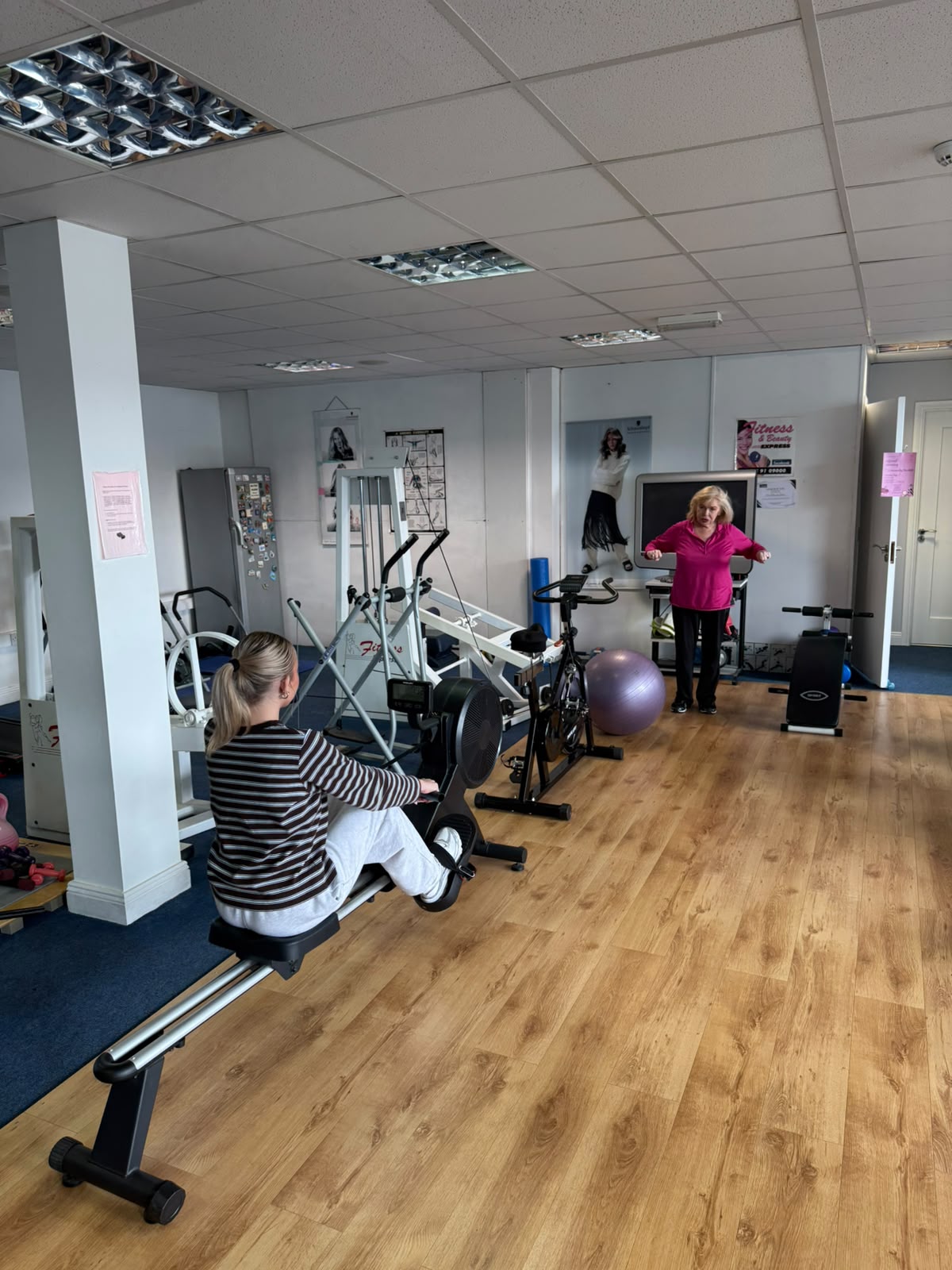 Coach giving one-to-one guidance to a member on the rowing machine